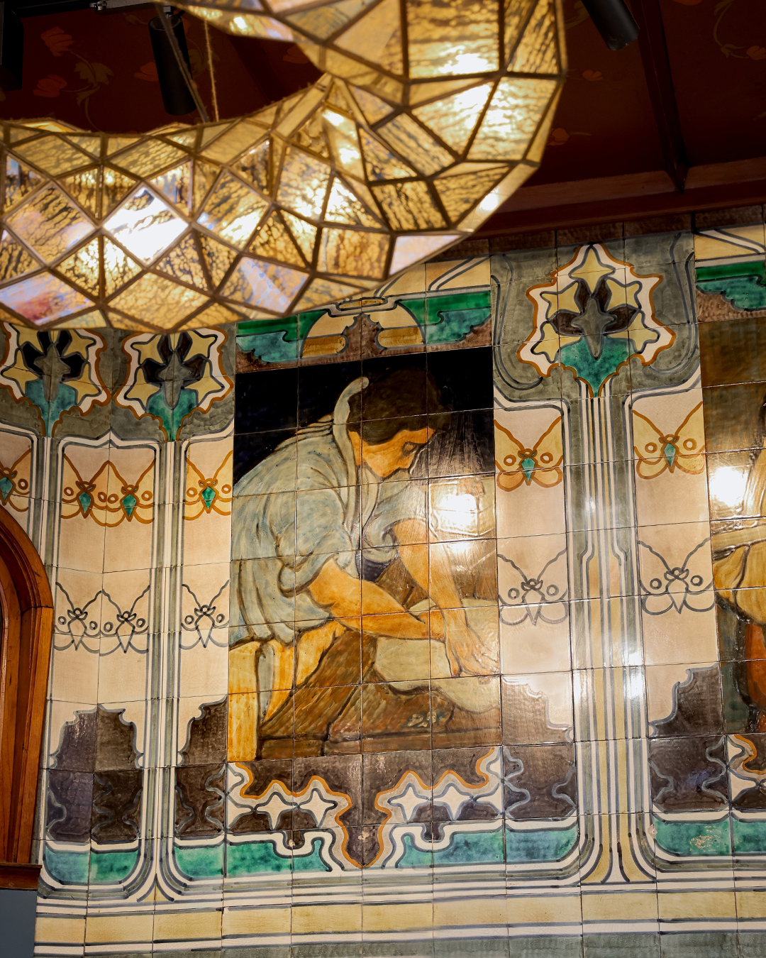 Hans Egstorf decorative tiled wall with artistic design and stained glass ceiling light fixture.
