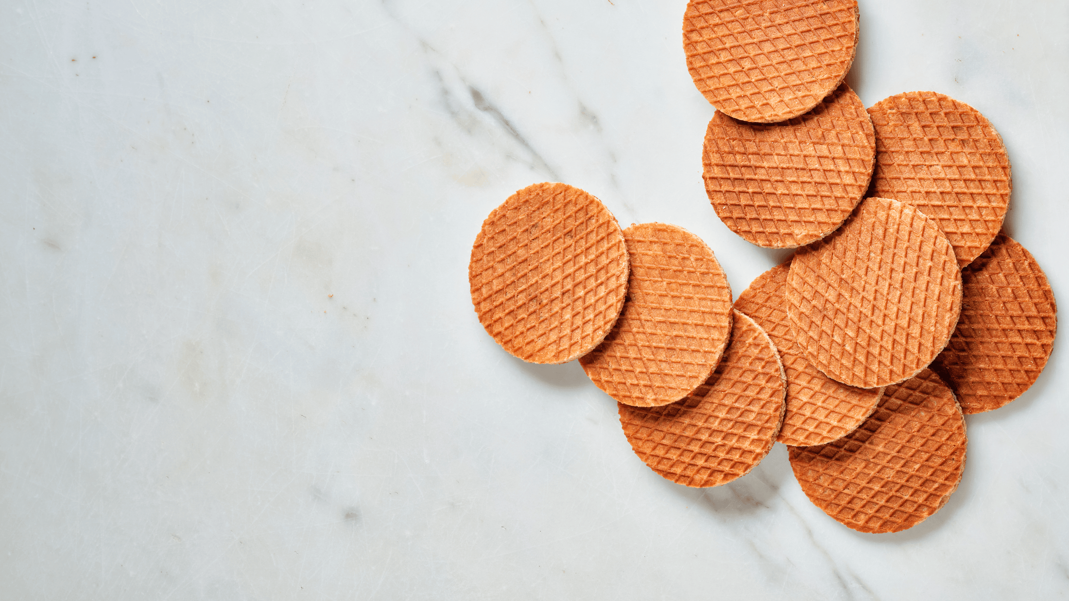 Round, brown stroopwafels on a marble surface