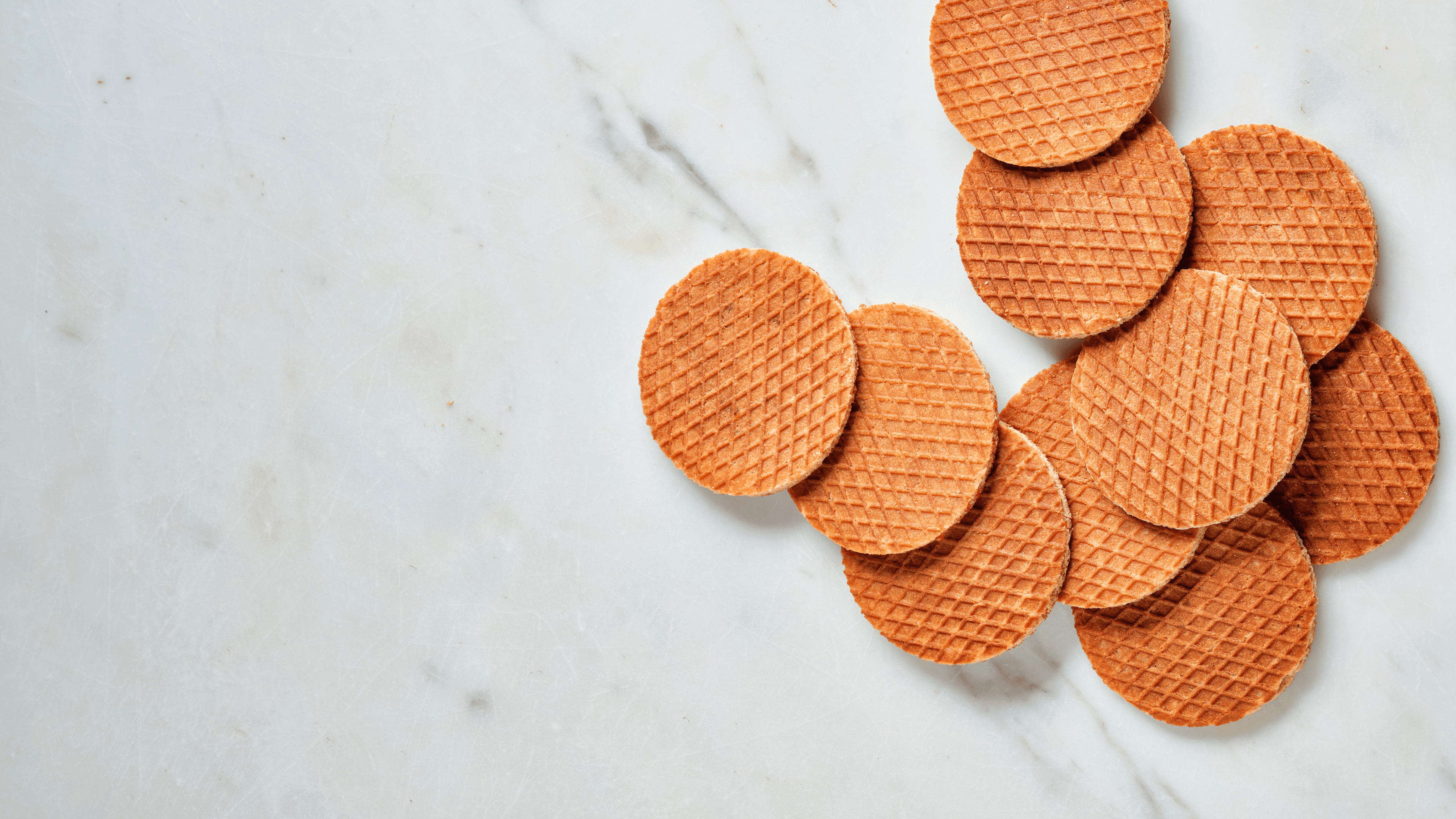 Round, brown stroopwafels on a marble surface